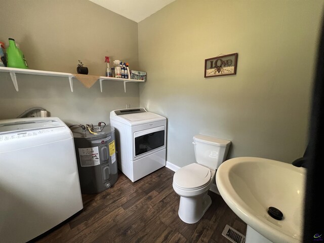 laundry area with electric water heater, washer / dryer, sink, and dark wood-type flooring