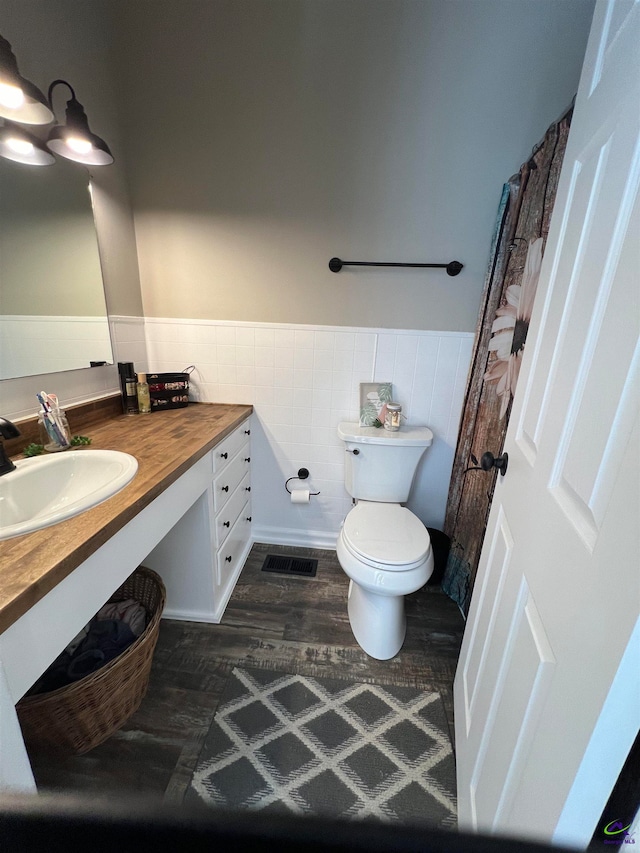 bathroom featuring tile walls, wood-type flooring, toilet, and vanity