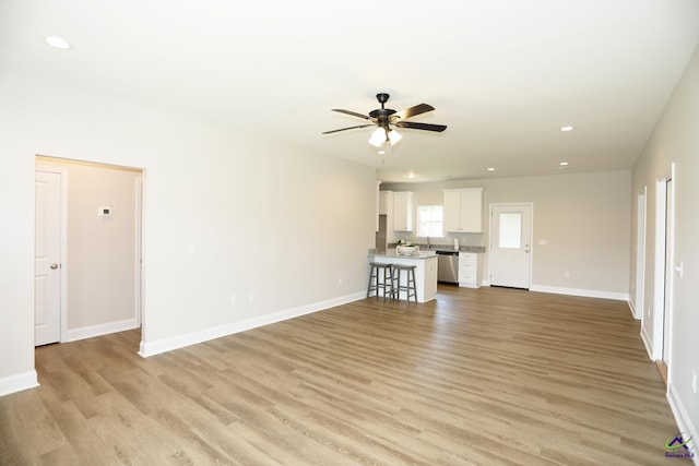 unfurnished living room featuring ceiling fan and light wood-type flooring