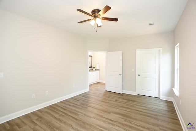 unfurnished bedroom with ensuite bathroom, ceiling fan, and wood-type flooring