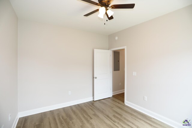 unfurnished room featuring ceiling fan, light hardwood / wood-style floors, and electric panel