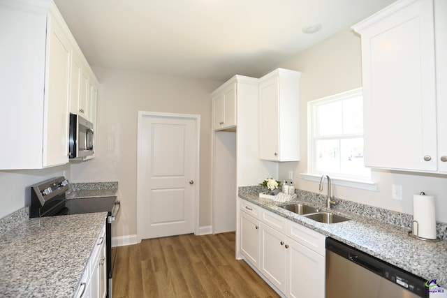 kitchen featuring white cabinets, light stone counters, stainless steel appliances, hardwood / wood-style floors, and sink