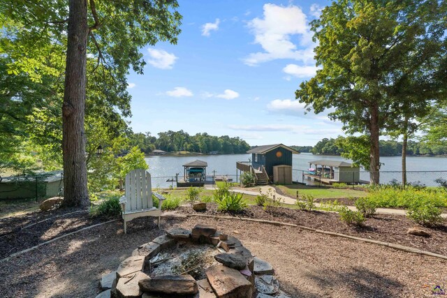 view of yard with a water view, a boat dock, and an outdoor fire pit