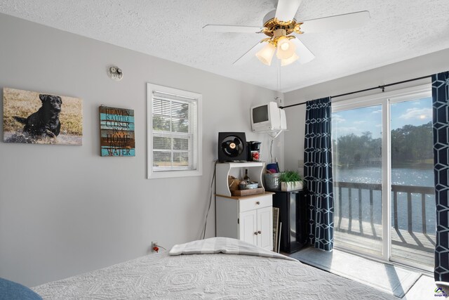 bedroom with multiple windows, a textured ceiling, ceiling fan, and access to outside