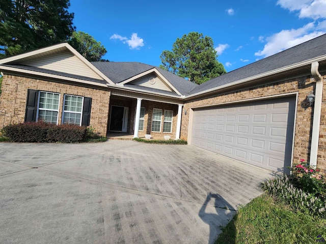 ranch-style home with a garage, driveway, brick siding, and a shingled roof