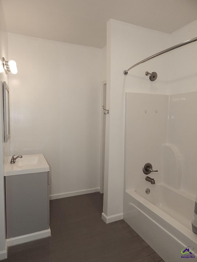 bathroom featuring vanity, wood finished floors, washtub / shower combination, and baseboards