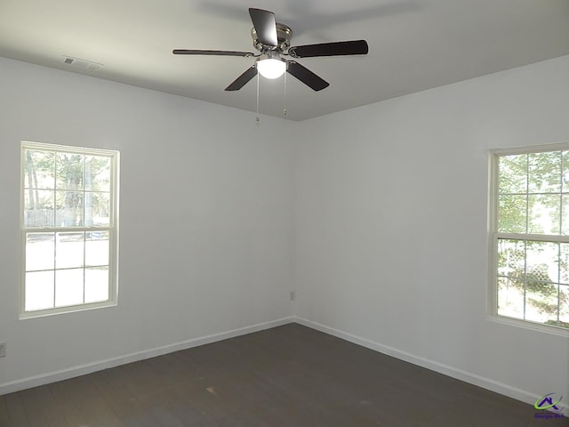 spare room with dark wood-style floors, visible vents, baseboards, and a ceiling fan