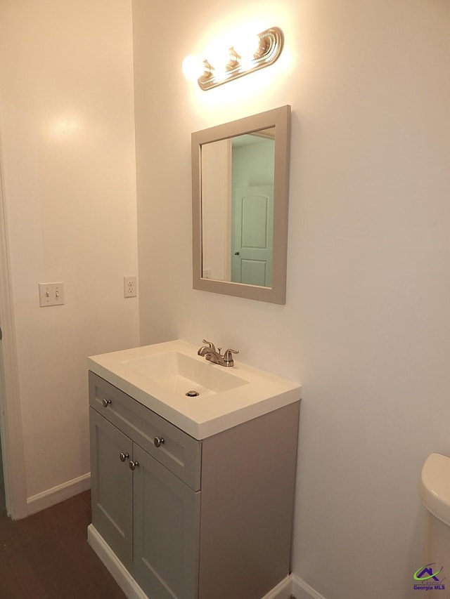 half bath with toilet, vanity, and baseboards