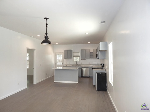 kitchen featuring a center island, light countertops, gray cabinetry, stainless steel dishwasher, and a sink