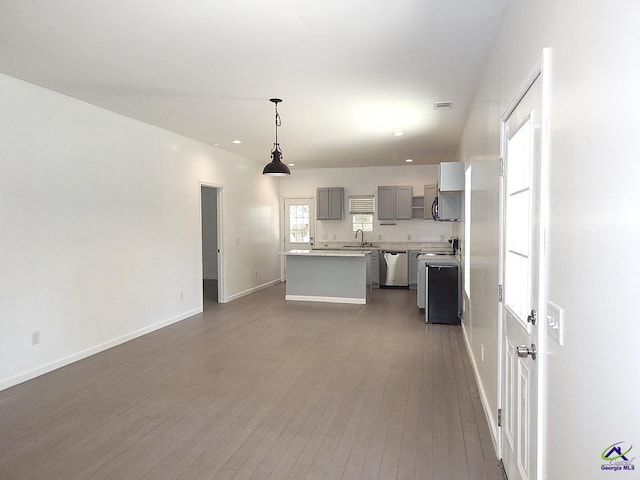 kitchen featuring dark wood finished floors, dishwasher, a center island, gray cabinets, and a sink