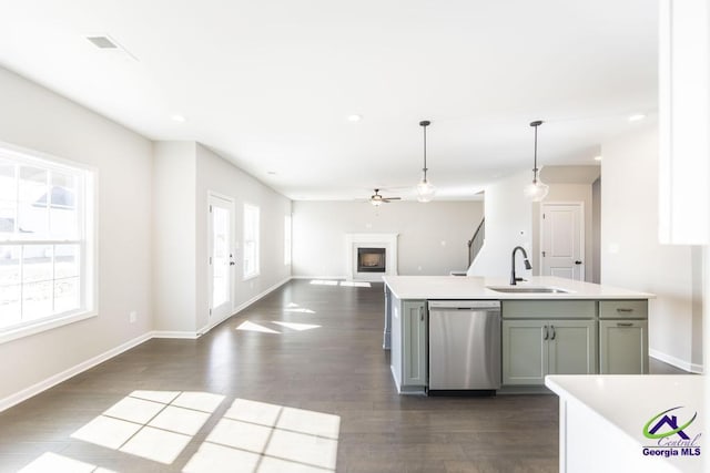 kitchen with a sink, dark wood-style floors, a fireplace, light countertops, and dishwasher