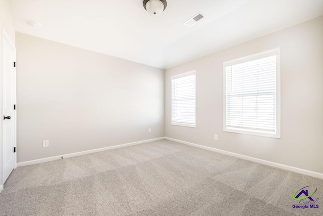 unfurnished room with visible vents, light carpet, and baseboards