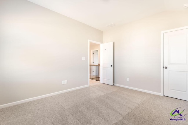 unfurnished bedroom with vaulted ceiling and light carpet