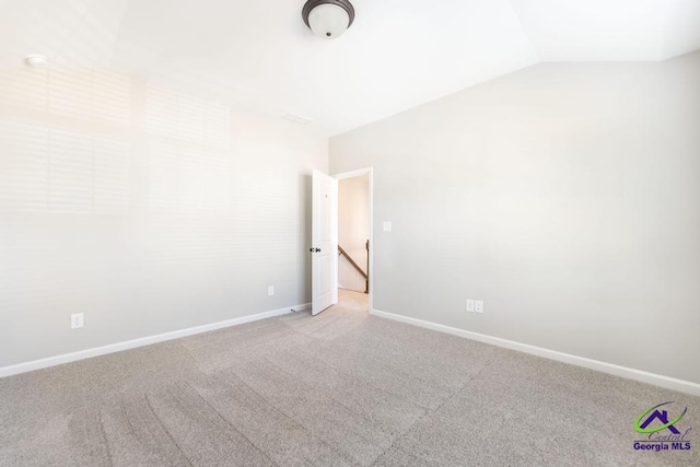 carpeted spare room with baseboards and vaulted ceiling