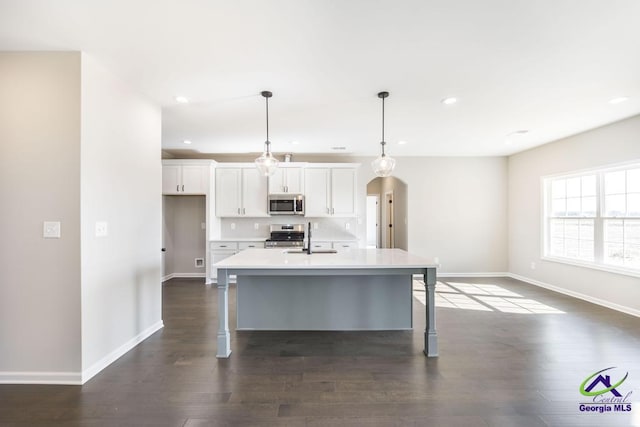 kitchen with a breakfast bar area, appliances with stainless steel finishes, arched walkways, white cabinetry, and a sink