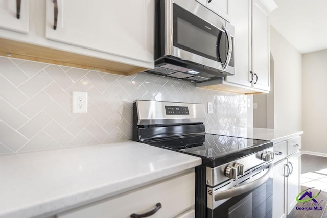 kitchen with decorative backsplash, appliances with stainless steel finishes, white cabinetry, and light countertops