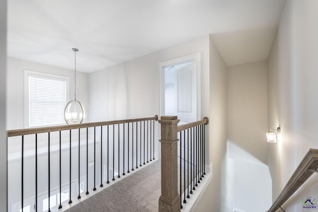 corridor with an inviting chandelier and carpet flooring