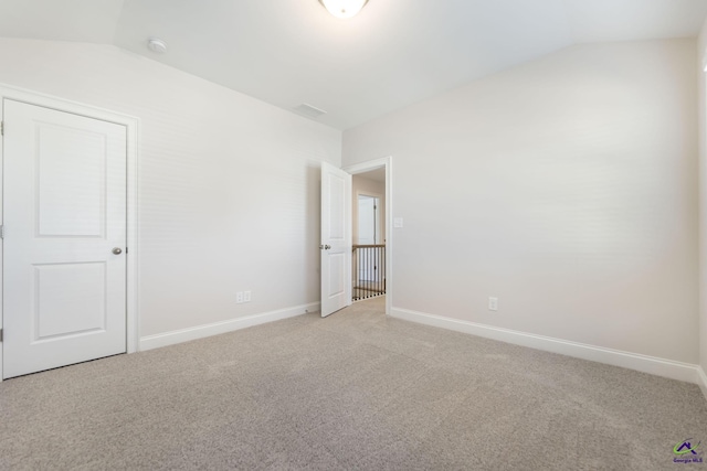 carpeted empty room featuring lofted ceiling