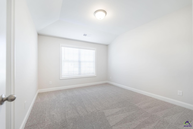 empty room featuring carpet and vaulted ceiling