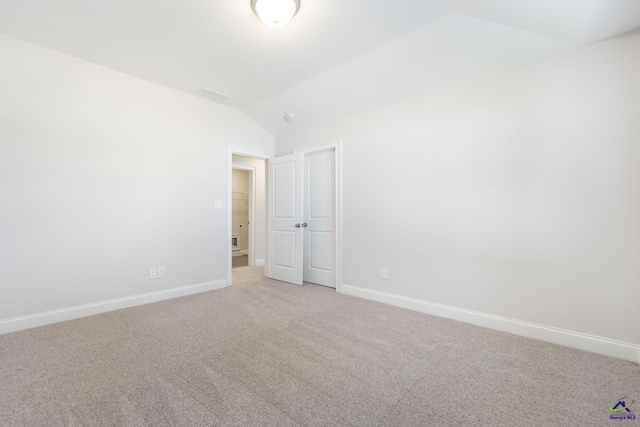 carpeted empty room featuring lofted ceiling