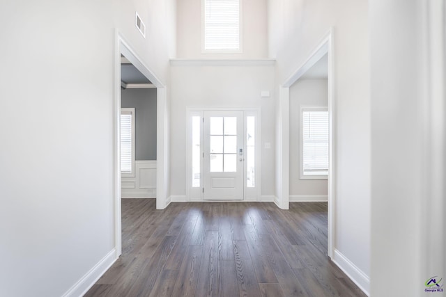 foyer entrance with dark wood-type flooring and crown molding