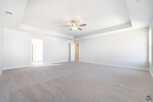 carpeted spare room with ceiling fan and a raised ceiling