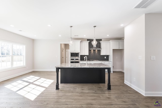 kitchen with a breakfast bar, white cabinetry, stainless steel appliances, and a kitchen island with sink