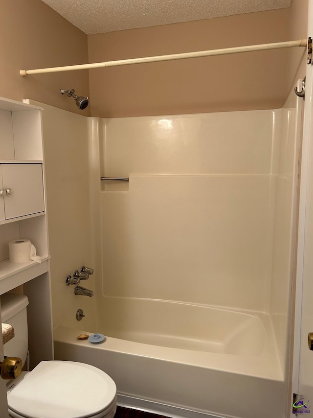 bathroom with a textured ceiling, toilet, and  shower combination