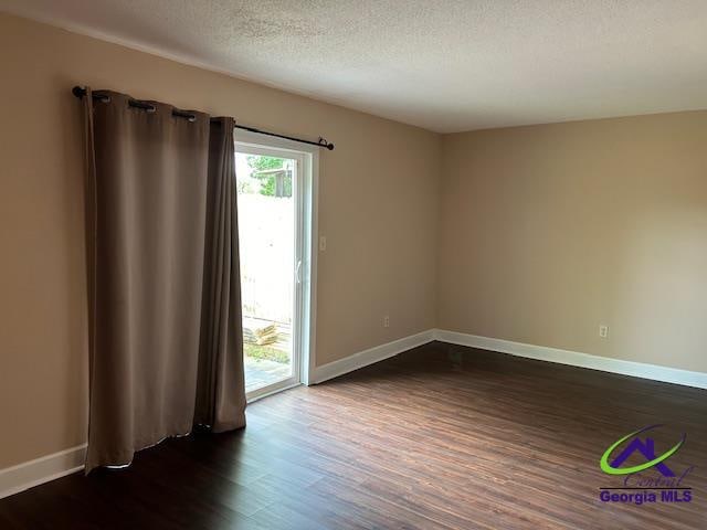 spare room featuring dark hardwood / wood-style flooring and a textured ceiling