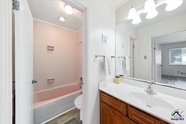 full bathroom with crown molding, tiled shower / bath combo, vanity, and toilet