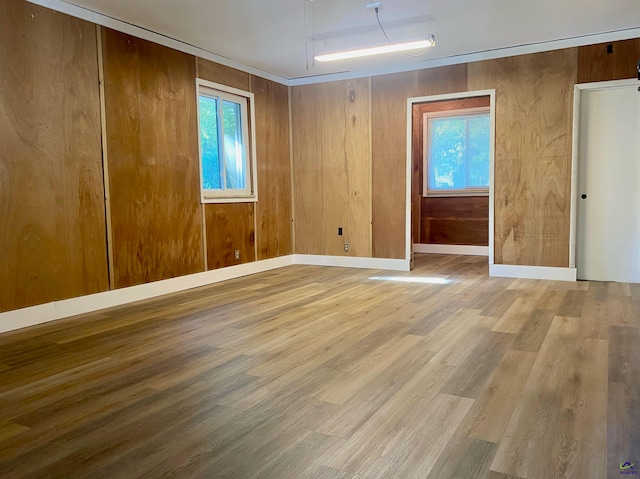 empty room with wood-type flooring, wood walls, and plenty of natural light