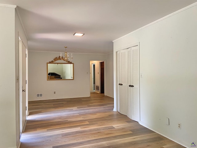 hallway featuring an inviting chandelier, light hardwood / wood-style flooring, and ornamental molding