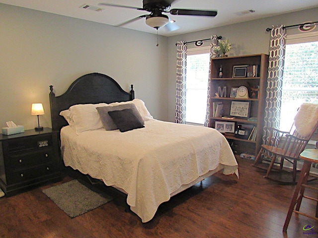 bedroom featuring multiple windows, dark hardwood / wood-style floors, and ceiling fan