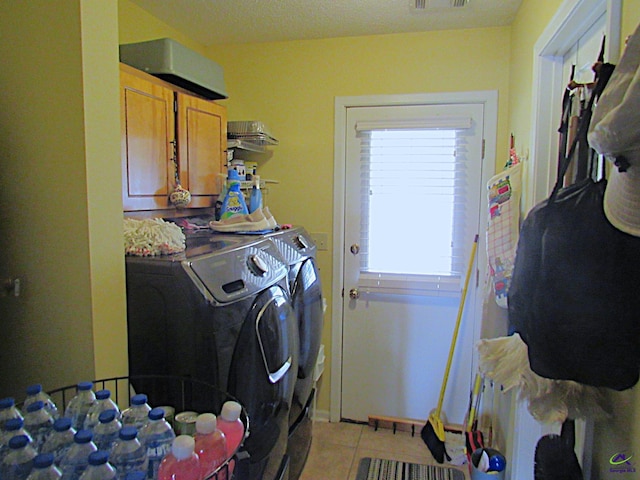 washroom featuring cabinets, light tile patterned floors, and washer and dryer