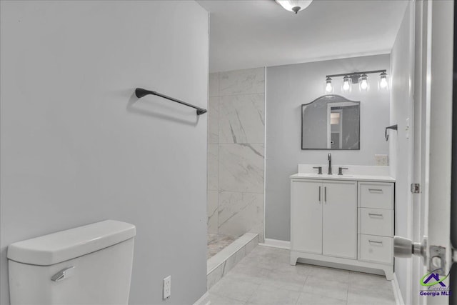 bathroom with toilet, vanity, a tile shower, and tile patterned floors