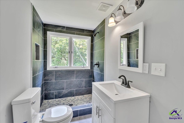 bathroom featuring toilet, vanity, and a tile shower