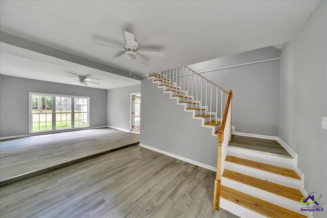 staircase with hardwood / wood-style flooring and ceiling fan