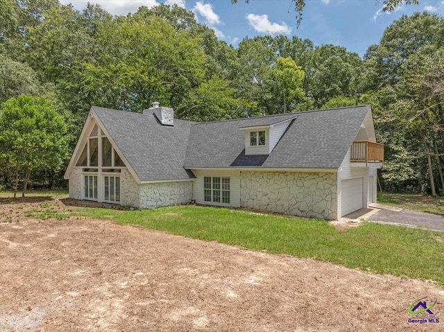 rear view of property with a lawn, a balcony, and a garage