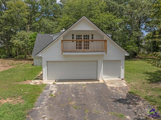 view of front property featuring a balcony, a garage, and a front lawn