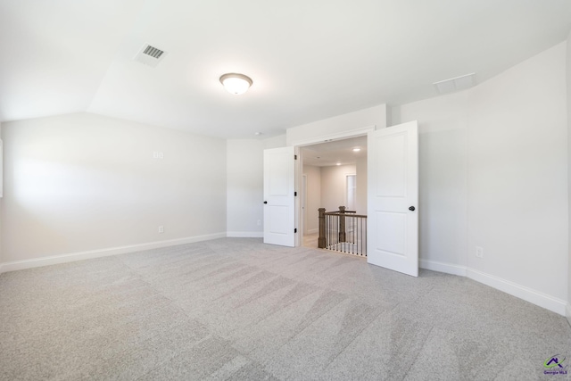 carpeted empty room with lofted ceiling