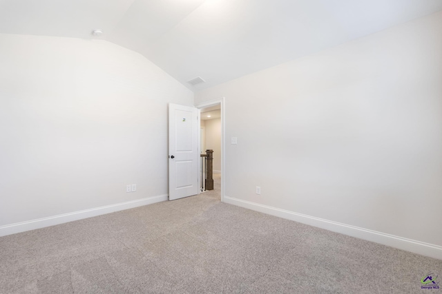 carpeted spare room with vaulted ceiling