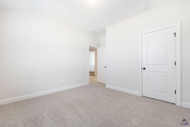 carpeted spare room with lofted ceiling