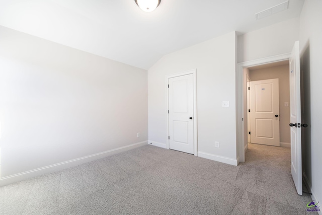 unfurnished bedroom with light carpet, a closet, and lofted ceiling