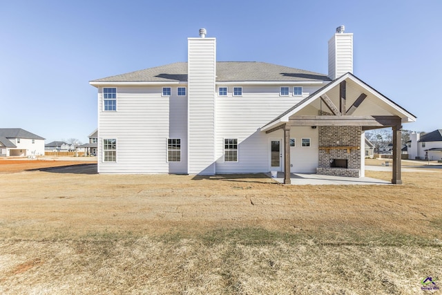 rear view of property with a brick fireplace, a patio area, and a yard