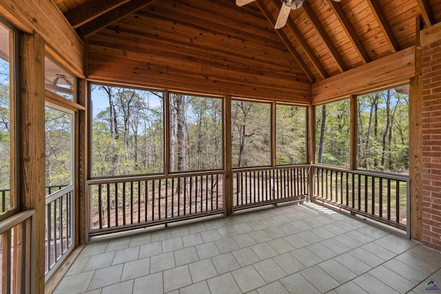 unfurnished sunroom featuring ceiling fan, wood ceiling, and vaulted ceiling with beams