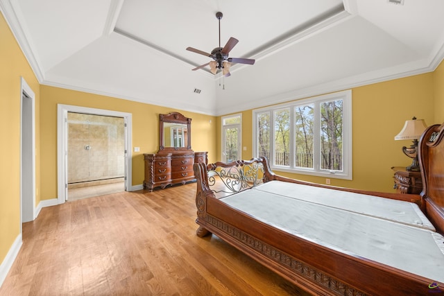 bedroom with ceiling fan, ornamental molding, a tray ceiling, and light hardwood / wood-style floors