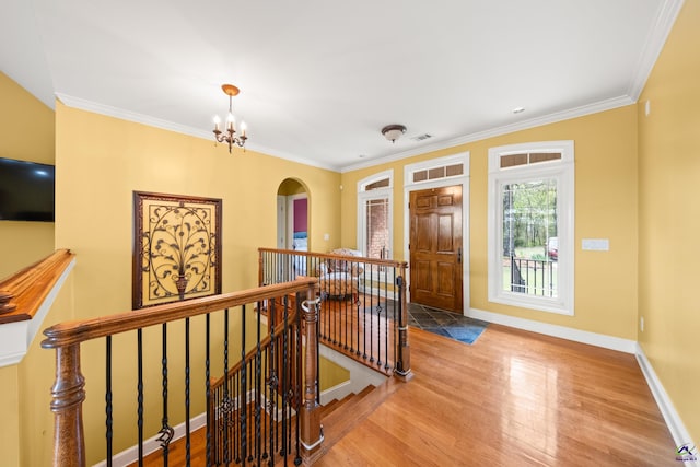 entryway with crown molding, wood-type flooring, and a chandelier