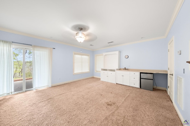 interior space featuring built in desk, ornamental molding, sink, light colored carpet, and ceiling fan