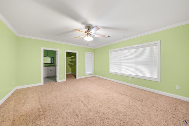 unfurnished bedroom featuring crown molding, light colored carpet, ceiling fan, and ensuite bathroom