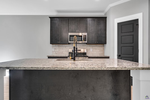 285 Lakeview Dr, Macon, GA 31211 - kitchen with stainless steel microwave, a sink, tasteful backsplash, a kitchen island with sink, and crown molding